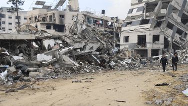 Palestinos caminan junto a un edificio destruido en el bombardeo israelí de la Franja de Gaza, en Ciudad de Gaza, el miércoles 3 de enero de 2024. (AP Foto/Mohammed Hajjar)