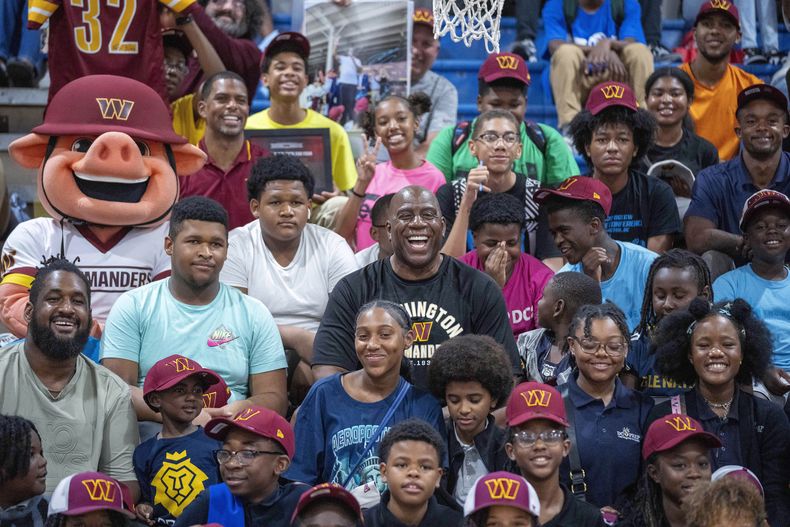 El dueño de los Commanders de Washington Magic Johnson posa con los niños del Boys & Girls Club en Washington como parte de los festejos del inicio de temporada con los nuevos dueños del equipo el jueves 7 de septiembre del 2023. (AP Foto/Alex Brandon)
