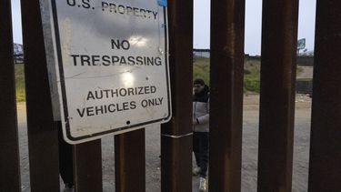 Migrantes esperan entre las vallas fronterizas que separan a Tijuana, México, de San Diego, EEUU, para solicitar asilo a las autoridades estadounidenses, el viernes 12 de abril de 2024, vistos desde San Diego. (AP Foto/Gregory Bull)