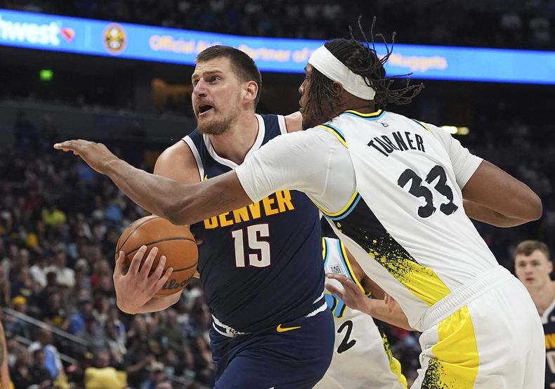 El pívot de los Nuggets de Denver, Nikola Jokic, a la izquierda, pasa junto al pívot de los Pacers de Indiana, Myles Turner, a la derecha, en la primera mitad de un partido de baloncesto de la NBA, el domingo 6 de abril de 2025, en Denver. (AP Foto/David Zalubowski)