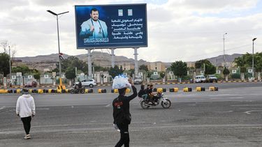 Un vendedor pasa bajo un cartel con la imagen del líder hutí Abdul Malik al-Houthi y la frase la acusación saudí contra nuestra gente merece describirse como la mentira del siglo, en Saná, Yemen, el lunes 5 de octubre de 2026. (AP Foto/Osamah Abdulrahman)