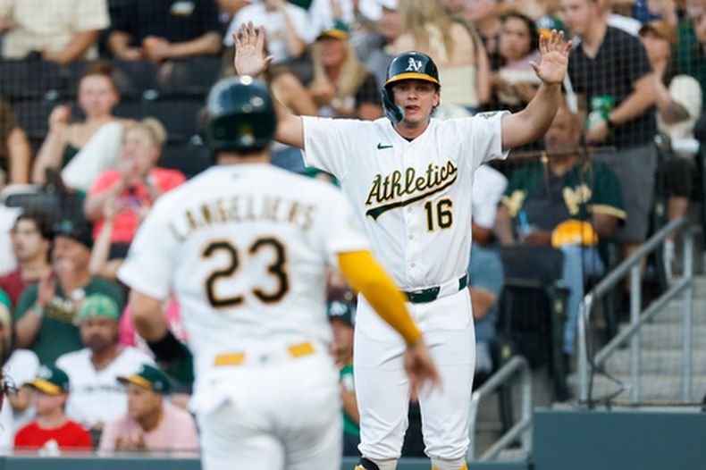 Nick Kurtz (16), de los Atléticos, observa a Shea Langeliers (23) correr hacia el plato mientras ambos anotan con un sencillo de Jacob Wilson durante la primera entrada del juego de béisbol de Grandes Ligas contra los Rockies de Colorado, el sábado 13 de junio de 2026, en Las Vegas. (AP Foto/Caroline Brehman)