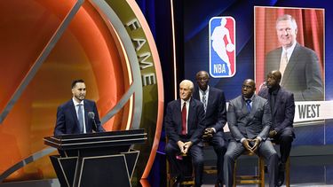 Jonnie West, a la izquierda, habla durante la consagración de su difunto padre Jerry West en el Salón de la Fama del Baloncesto mientras, de izquierda a derecha, Pat Riley, Bob McAdoo, Magic Johnson y James Worthy lo acompañan en el escenario, el domingo 13 de octubre de 2024 en Springfield, Massachusetts. (Foto AP/Jessica Hill)