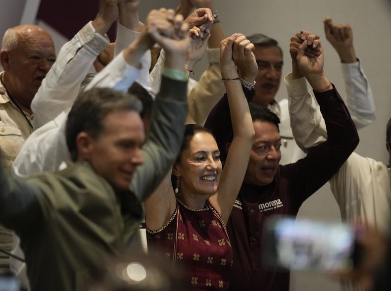 Una de las posibles candidatas presidenciales de Morena, partido gobernante en México, y alcaldesa de Ciudad de México, Claudia Sheinbaum, en el centro, levanta sus brazos en una conferencia de prensa en un hotel en Ciudad de México, el domingo 11 de junio de 2023. El presidente mexicano y presidente del partido, Andrés Manuel López Obrador, dio a conocer las reglas que deben seguir los aspirantes a candidatos del oficialismo ante las elecciones presidenciales de 2024 y la fecha de las primarias en que se definirá quién ocupará la nominación del partido. (AP Foto/Fernando Llano)