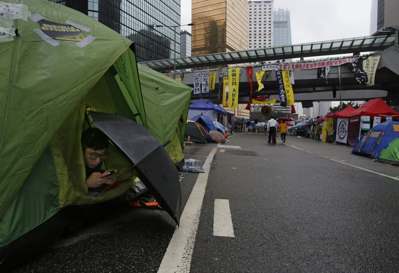 Un manifestante pro democracia consulta su tel&eacute;fono movil en una tienda de campa&ntilde;a en una zona ocupada fuera de la sede del gobierno en el distrito de Admiralty, en Hong Kong,el 8 de noviembre de 2014. (Foto AP/Vincent Yu)