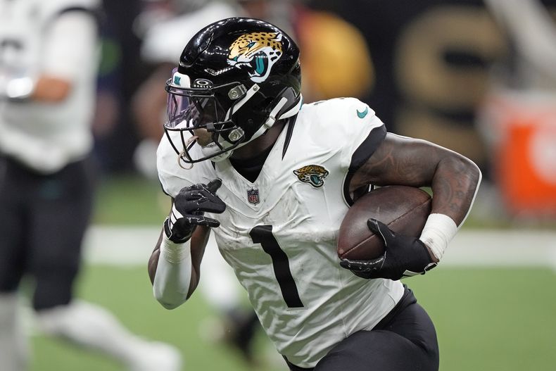 El running back de los Jaguars de Jacksonville Travis Etienne Jr. (1) lleva el balón en la primera mitad del partido ante los Saints de Nueva Orleans, el jueves 19 de octubre de 2023, en Nueva Orleans. (AP Foto/Gerald Herbert)