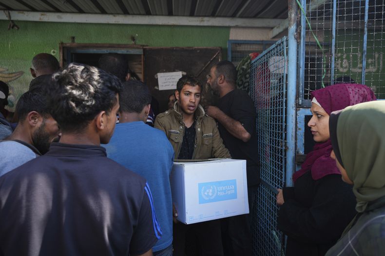Palestinos reciben ayuda distribuida por UNRWA, la agencia de la ONU que ayuda a los refugiados palestinos, en el campo de refugiados de Nusairat, Gaza, el 5 de noviembre de 2024. (AP Foto/Abdel Kareem Hana)