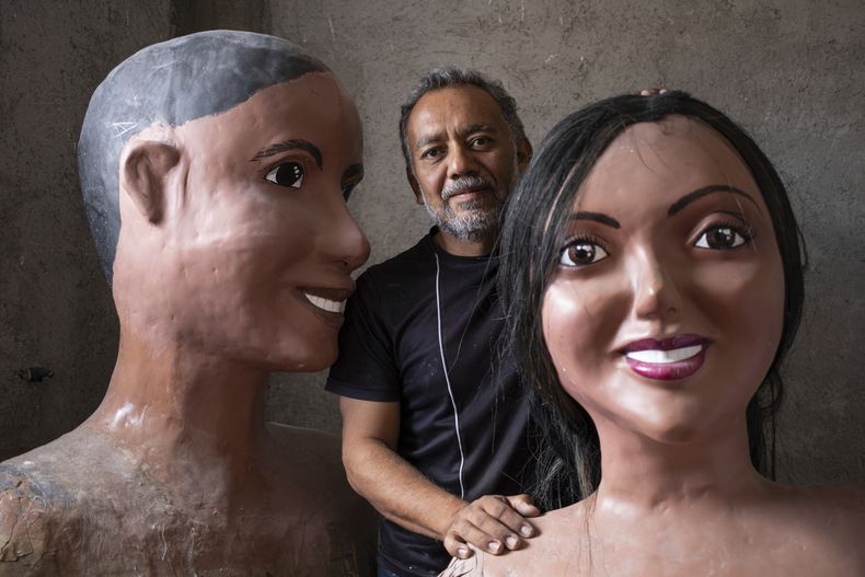 Tonatiuh Estrada, un artista oaxaqueño, posa con dos de sus obras en Oaxaca, México, el domingo 16 de julio de 2023. Estrada recibió el encargo de crear figuras que representaran a mujeres de las ocho regiones del estado. Las representaciones de tres metros de altura se utilizan tradicionalmente para las calendas, como los oaxaqueños llaman a las procesiones durante las fiestas católicas en honor a sus patrones o santos. (AP Foto/María Alférez)