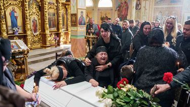 Una madre rodeada por familiares llora sentada junto al ataúd de su hijo Illia Honcharenko, de 14 años, asesinado por un ataque ruso con cohete contra una vivienda el 30 de septiembre, durante su funeral en Vyshhorod, en la región de Kiev, Ucrania el viernes 2 de octubre de 2026. (AP Foto/Evgeniy Maloletka)