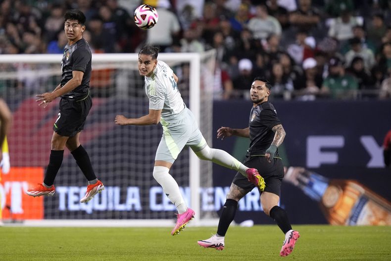 Alexis Peña, centro, de México, cabecea el balón para despejar ante la mirada de Miguel Terceros, izquierda, durante el primer tiempo de un partido amistoso entre las selecciones nacionales de México y Bolivia, el viernes 31 de mayo de 2024, en Chicago. (AP Foto/Charles Rex Arbogast)