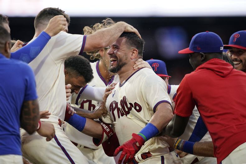 Kyle Schwarber de los Filis de Filadelfia celebra con sus compañeros tras batear el elevado de sacrificio ante el relevista de los Padres de San Diego Tim Hill en la 12ma entrada del juego del domingo 16 de julio del 2023. (AP Foto/Matt Slocum)