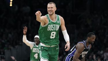 Kristaps Porzingis, de los Celtics de Boston, celebra un triple en la primera mitad del partido de la NBA ante los Kings de Sacramento, el viernes 5 de abril de 2024, en Boston. Al fondo, Hariso Barnes, de los Kings. (AP Foto/Michael Dwyer)