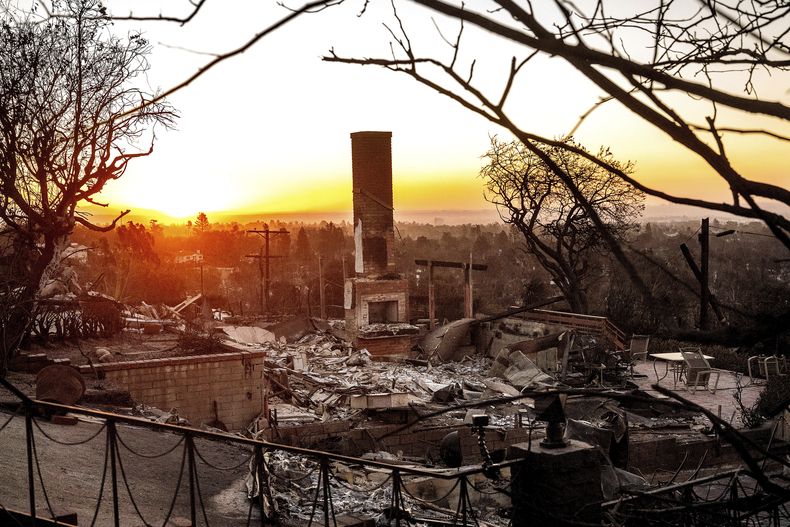 Amanece en el horizonte, detrás de una vivienda devastada por el incendio en la comunidad de Pacific Palisades, el domingo 12 de enero de 2025, en Los Ángeles. (AP Foto/Noah Berger)