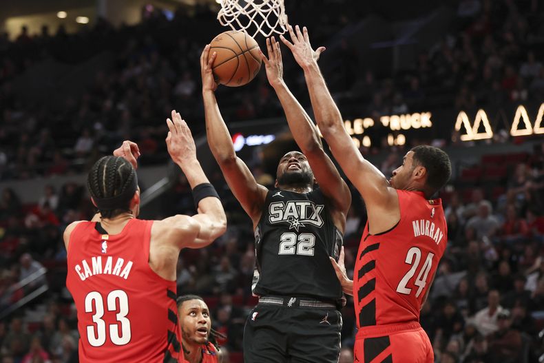 Malaki Branham (22), de los Spurs de San Antonio, busca encestar entre Toumani Camara (33) y Kris Murray (24), de los Trail Blazers de Portland, durante la segunda mitad del juego de baloncesto de la NBA, el domingo 6 de abril de 2025, en Portland, Oregon. (AP Foto/Amanda Loman)