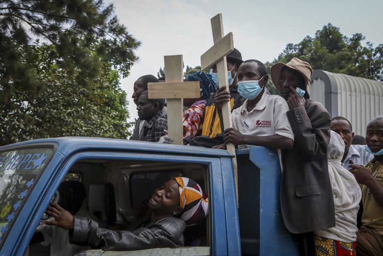 Familiares en la parte trasera de una camioneta con los ataúdes de las personas que murieron en un ataque a una escuela, en Bwera, Uganda, el domingo 18 de junio de 2023. (AP Foto/Hajarah Nalwadda)