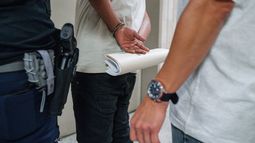 ARCHIVO – Un hombre sostiene sus papeles de inmigración estando esposado tras ser detenido por agentes del Servicio de Inmigración y Control de Aduanas (ICE, por sus siglas en inglés) fuera de un tribunal de inmigración, el 17 de junio de 2025, en el edificio federal Jacob K. Javits en Nueva York. (AP Photo/Olga Fedorova, Archivo)