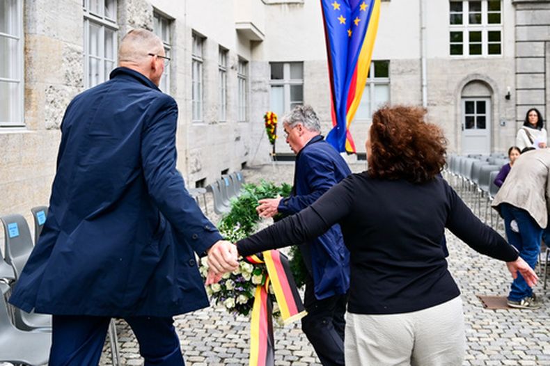 Tobias Korenke, sobrino nieto de un pastor ejecutado por los nazis, intenta retirar una corona del partido AfD de extrema derecha alemán durante un acto conmemorativo organizado por el gobierno federal en el patio del Ministerio de Defensa con motivo del Día Nacional de Recuerdo por la Resistencia contra el régimen nazi en Berlín, el 20 de julio de 2026. (Foto, Sebastian Christoph Gollnow/dpa vía AP)