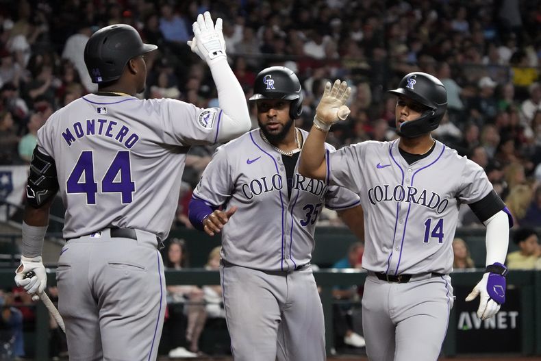 El campocorto de los Rockies de Colorado, Ezequiel Tovar (14), celebra con el antesalista Elehuris Montero (44) y el receptor Elías Díaz después de conectar un jonrón de dos carreras contra los Diamondbacks de Arizona en la segunda entrada durante un juego de béisbol, el sábado 30 de marzo de 2024, en Phoenix. (AP Foto/Rick Scuteri)