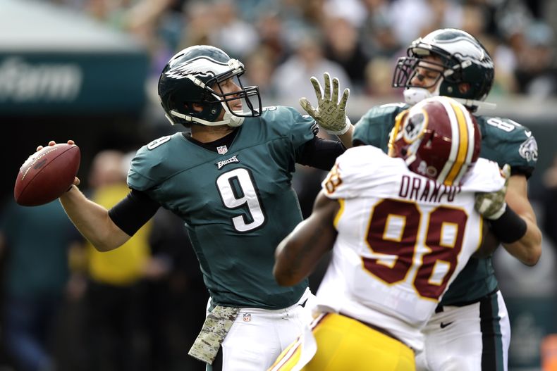 Nick Foles (9), quarterback de Eagles de Filadelfia, realiza un pase mientras lo presiona el linebacker de los Redskins de Washington Brian Orakpo durante la primera mitad del juego del domingo 17 de noviembre de 2013, en Filadelfia. (Foto AP/Matt Rourke)