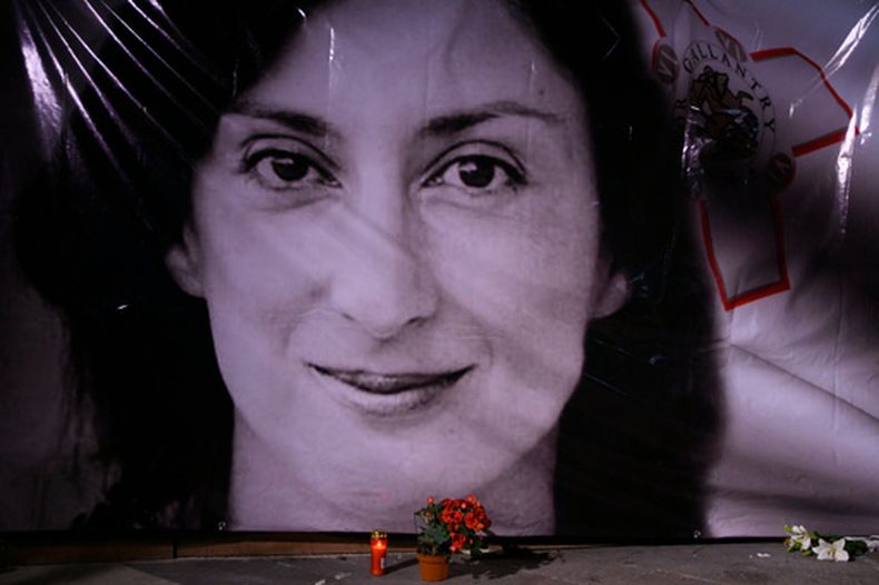 Flores y una vela frente a un retrato de la asesinada periodista investigativa Daphne Caruana Galizia en La Valeta, Malta, el 16 de octubre del 2018. (AP foto/Jonathan Borg)