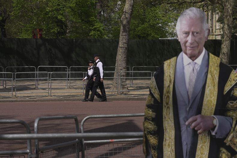 Agentes de la policía vigilan una calle detrás de un cartón con la imagen del rey Carlos III, en Londres, el miércoles 3 de mayo de 2023, días antes de la coronación del monarca británico. (AP Foto/Kin Cheung)