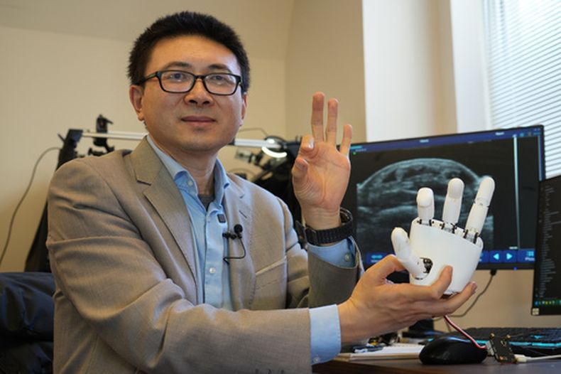 Xuanhe Zhao, profesor de ingeniería mecánica en el Instituto de Tecnología de Massachusetts, posa para una foto con una pulsera de ultrasonidos que puede ayudar a una mano robótica a imitar movimientos completos de manos en Cambridge, Massachusetts, el martes 14 de abril de 2026. (AP Foto/Rodrique Ngowi)