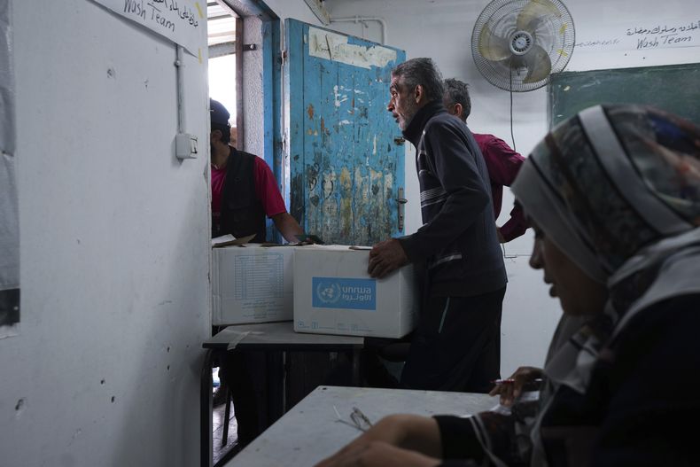 Palestinos reciben ayuda distribuida por la Agencia de las Naciones Unidas para los Refugiados de Palestina en Oriente Medio (UNRWA, por sus siglas en inglés), en el campo de refugiados de Nusairat, en Gaza, el martes 5 de noviembre de 2024. (Foto AP/Abdel Kareem Hana)