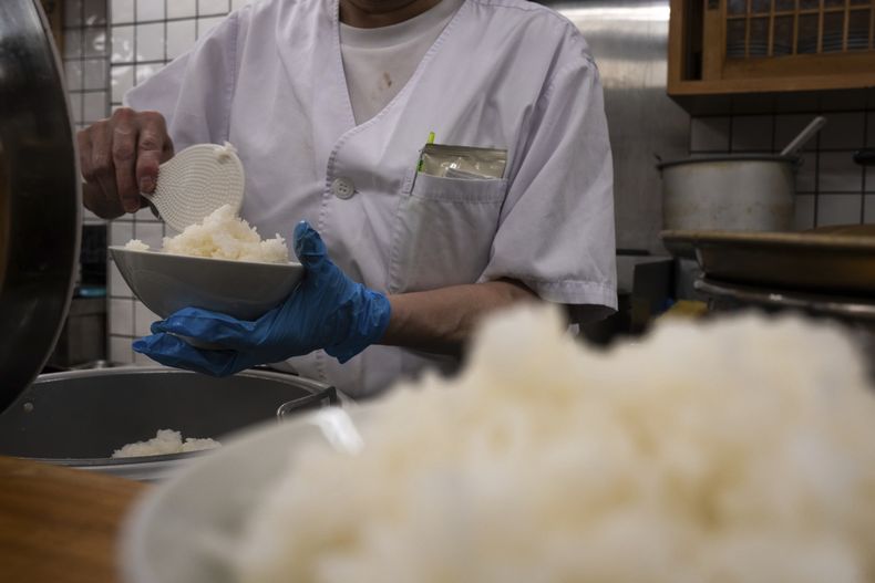 Un empleado prepara un tazón de arroz en un restaurante de Tokio, el jueves 22 de mayo de 2025. (AP Foto/Louise Delmotte)