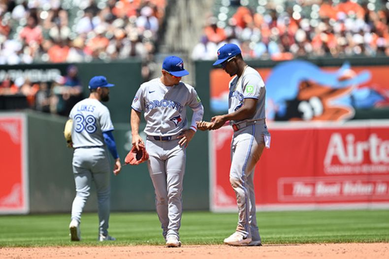 El jardinero derecho de los Azulejos de Toronto, Jesús Sánchez (derecha), se mira la mano después de que arrojaran algo desde las gradas durante un partido de béisbol contra los Orioles de Baltimore, el domingo 31 de mayo de 2026, en Baltimore. (Foto AP/Gail Burton)