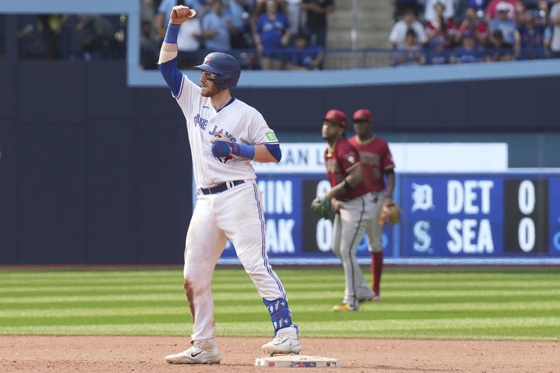 Danny Jansen de los Azulejos de Toronto celebra sobre la segunda base luego de conectar un doblete de tres carreras ante Scott McCough de los Diamondbacks de Arizona, durante el octavo episodio del juego en Toronto. Domingo 16 de julio de 2023. (Chris Young/The Canadian Press via AP)