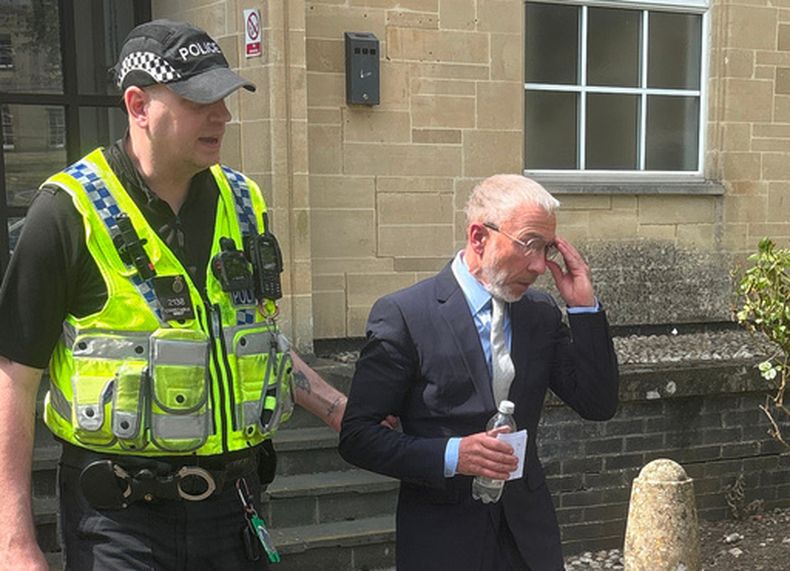 James Holder, cofundador de la firma de ropa Superdry, es escoltado por un policía a la salida del Tribunal de Magistrados de Cirencester, Inglaterra, el viernes 1 de mayo de 2026. (Rod Minchin/PA vía AP)