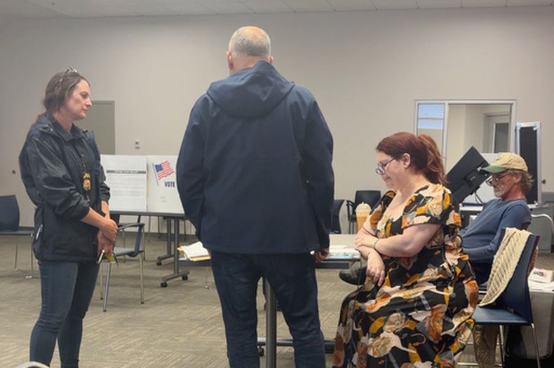 En esta imagen de video entregado por Sheilia Milledge, Paigelynne Gonyea (der) recibe un formulario en un centro de votación en Syracuse, Nueva York, el 23 de junio del 2026. (Sheilia Milledge via AP)