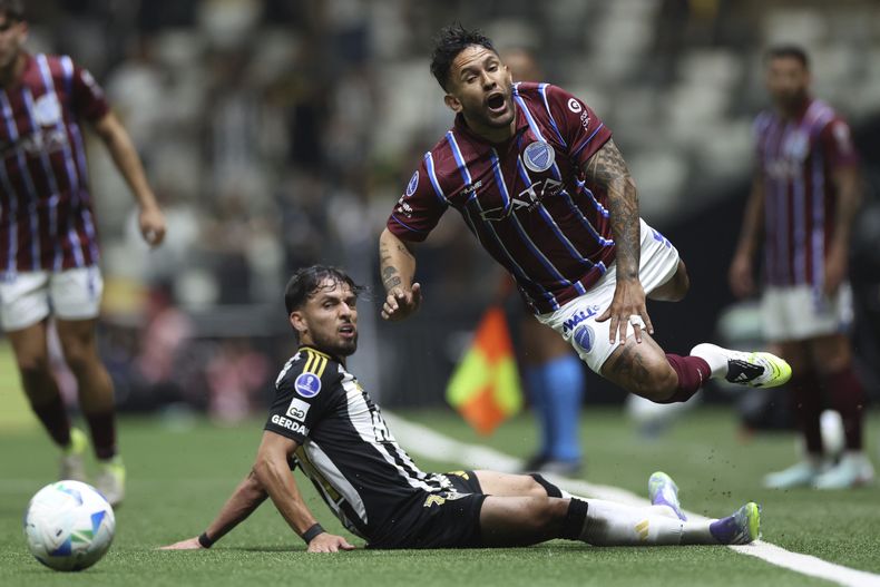 Gabriel Teixeira (izquierda) de Atlético Mineiro de Brasil y Walter Montoya de Godoy Cruz de Argentina en el partido de los octavos de final de la Copa Sudamericana, el jueves 14 de agosto de 2025, en Belo Horizonte, Brasil. (AP Foto/Tiago Trindade)