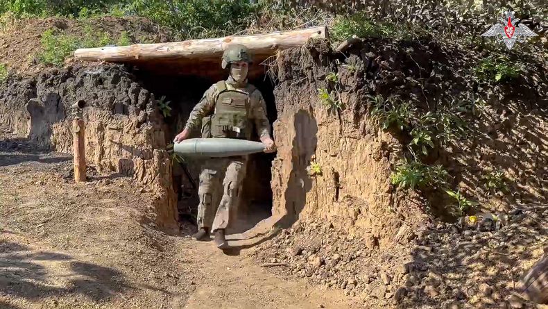 En esta foto, tomada de un video difundido por el Ministerio de Defensa ruso el sábado 10 de agosto de 2024, un militar ruso lleva un proyectil para el obús de 152 mm Msta-B para disparar hacia posiciones ucranianas en un lugar no revelado de Ucrania. (Servicio de prensa del Ministerio de Defensa ruso vía AP)