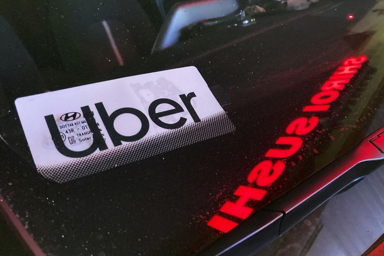 ARCHIVO - Un cartel de Uber en un auto en Glenview, Illinois, EEUU, 17 de diciembre de 2022. Las empresas de taxis por internet Uber y Lyft pagarán en conjunto 328 millones de dólares para resolver un pleito judicial por robo de salarios en Nueva York, informó la procuradora estatal Letitia James el jueves 2 de noviembre de 2023. (AP Foto/Nam Y. Huh, File)