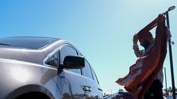 Un migrante ajusta su pañuelo en un estacionamiento tras ser detenido y procesado para recibir asilo por las autoridades de Estados Unidos, el martes 7 de mayo de 2024, en San Diego. (AP Foto/Ryan Sun)