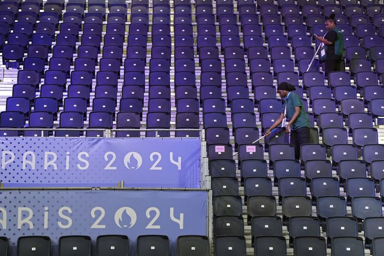 Empleados limpian las butacas de la Arena del Norte de París, sede del boxeo de los Juegos Olímpicos de París, el miércoles 24 de julio de 2024. (AP Foto/John Locher)