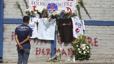 Un aficionado del Alianza se ve parado ante las ofrendas colocadas en memoria de aficionados muertos en una estampida en el estadio Cuscatlán ante el estadio, en San Salvador, El Salvador, el lunes 22 de mayo de 2023. Un juez de San Salvador ordenó que los cinco responsables -tres del club y dos del estadio- permanezcan en prisión preventiva mientras son procesados por el delito infracción a las reglas de seguridad en modalidad agravada. (AP Foto/Salvador Meléndez)