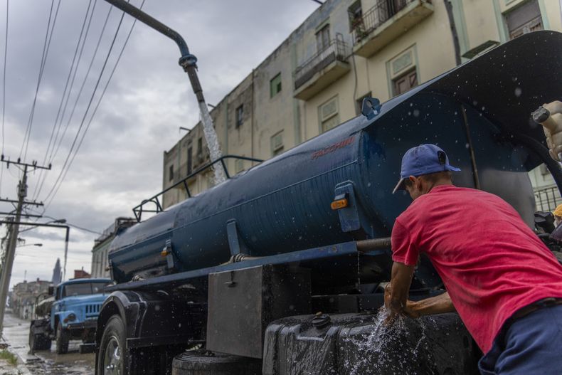 Un conductor de camión cisterna se lava las manos mientras rellena su camión con agua para transportarla a los edificios en medio de la escasez de agua en La Habana, Cuba, el martes 24 de septiembre de 2024. (AP Foto/Ramón Espinosa)