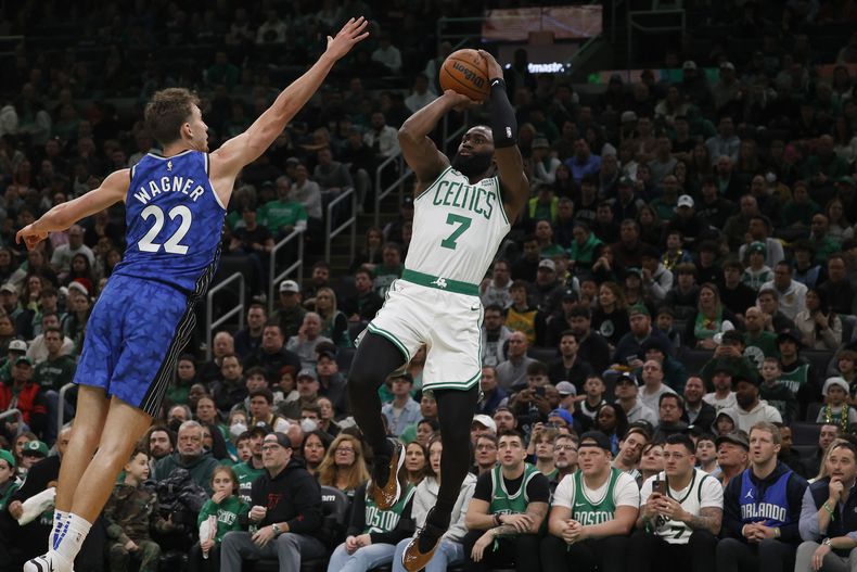 Jaylen Brown (7), escolta de los Celtics de Boston, dispara sobre el intento de bloqueo de Franz Wagner (22), alero del Magic de Orlando, durante la primera mitad del juego de baloncesto de la NBA, el domingo 17 de diciembre de 2023, en Boston. (AP Foto/Mary Schwalm)