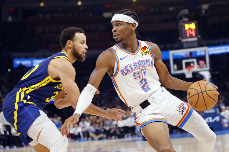 El armador del Thunder de Oklahoma City Shai Gilgeous-Alexander (2) gira alrededor del armador de los Warriors de Golden State, Stephen Curry durante la primera mitad del juego de la NBA, el viernes 8 de diciembre de 2023, en Oklahoma City. (AP Foto/Nate Billings)