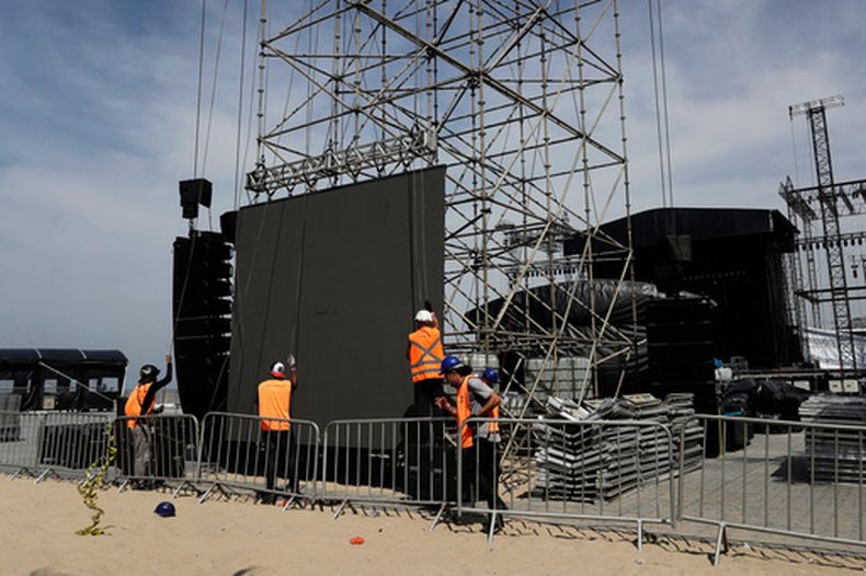 Trabajadores reanudan la construcción del escenario para un concierto de la estrella del pop colombiana Shakira después de la muerte de un trabajador en un accidente durante el montaje el día anterior, en la playa de Copacabana en Río de Janeiro, el lunes 27 de abril de 2026. (Foto AP/Bruna Prado)