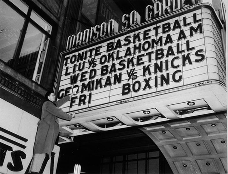 ARCHIVO - George Mikan, de los Lakers de Minneapolis Lakers pule el letrero de la marquesina del Madison Square Garden en Nueva York, el 13 de diciembre de 1949, para asegurarse de que su nombre brille con fuerza para el partido de baloncesto de la NBA. (Foto AP/Jacob Harris, archivo)