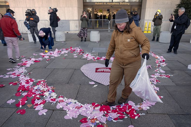 Manifestantes en apoyo de los trabajadores federales colocan mensajes por el Día de San Valentín dirigidos a ellos afuera del Departamento de Salud y Servicios Humanos, el viernes 14 de febrero de 2025, en Washington. (AP Foto/Mark Schiefelbein)