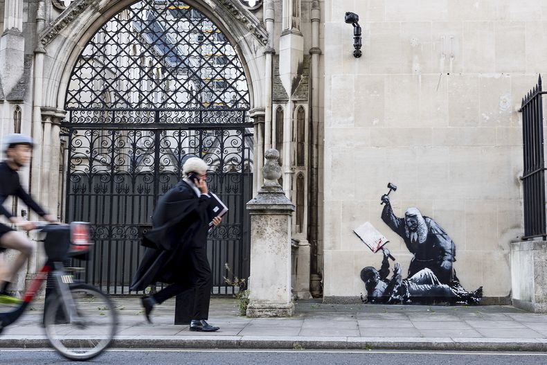 Fotografía sin fecha publicada por Banksy de la nueva obra de arte del artista que retrata a un juez golpeando a un manifestante con un mazo en los Tribunales Reales de Justicia de Londres. (Banksy via AP)