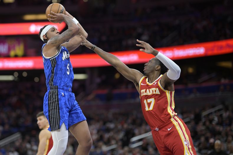 Paolo Banchero (5), del Magic de Orlando, dispara ante la presión del alero Onyeka Okongwu (17), de los Hawks de Atlanta, durante la primera mitad del juego de baloncesto de la NBA, el domingo 7 de enero de 2024, en Orlando, Florida. (AP Foto/Phelan M. Ebenhack)