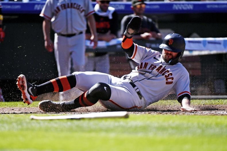 J.D. Davis de los Gigantes de San Francisco se desliza a salvo en el plato en la 5ta entrada del juego ante los Rockies de Colorado, en Denver. Domingo 17 de septiembre de 2023. (AP Foto/Geneva Heffernan)