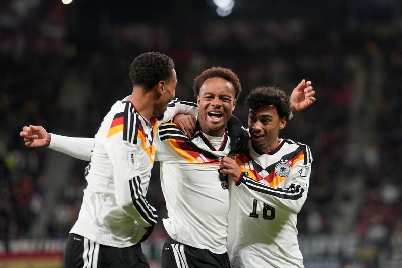 Assan Ouédraogo, de Alemania, al centro, celebra después de anotar durante un juego de fútbol de clasificación del grupo A para la Copa del Mundo entre Alemania y Eslovaquia en Leipzig, Alemania, el lunes 17 de noviembre de 2025. (AP Photo/Matthias Schrader)