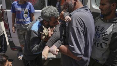 Palestinos sostienen el cuerpo de un bebé muerto rescatado de entre los escombros de un edificio destruido en un ataque aéreo israelí en Nuseirat, en la Franja de Gaza, el 14 de mayo de 2024. (AP Foto/Abdel Kareem Hana)