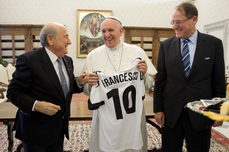 El papa Francisco, centro, sonr&iacute;e al recibir una camiseta con su nombre en una reuni&oacute;n con el presidente de la FIFA, Joseph Blatter, izquierda, en el Vaticano el viernes, 22 de noviembre de 2013. Imagen suministrada por el diario del Vatican